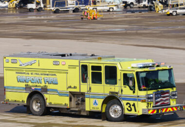 A Minneapolis–St. Paul International Airport fire truck, painted in its distinctive lime-yellow livery, is seen positioned on the tarmac. Marked “Airport Fire” and operated by the Metropolitan Airports Commission, the truck is equipped for rapid response to aircraft and runway emergencies. Its specialized design includes high-capacity foam systems and reinforced compartments for rescue tools, reflecting the critical role of airport fire units in ensuring safety across one of the Midwest’s busiest aviation hubs.