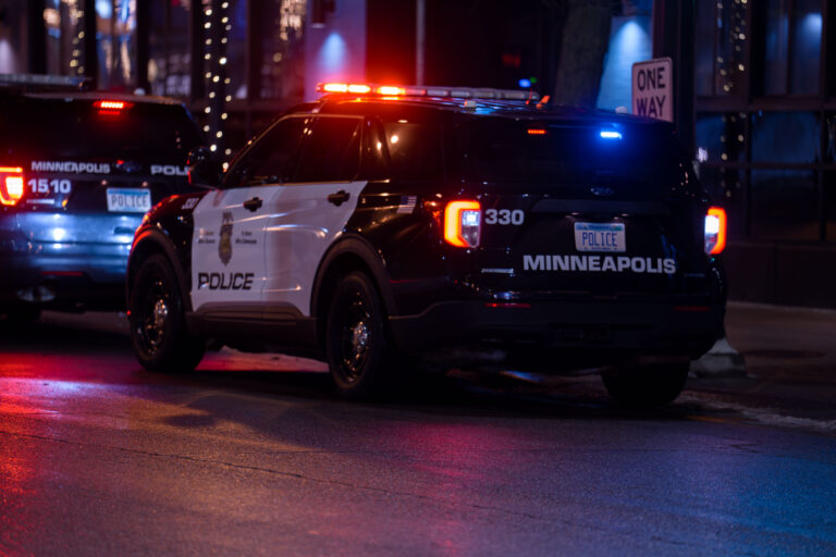 Minneapolis Squad Car in Uptown Minneapolis 2023 4 Minneapolis police SUVs parked on Lagoon Avenue in Uptown Minneapolis at night with lights flashing.