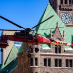 A heavy-lift Sikorsky S-64 Skycrane Helicopter in downtown Minneapolis bringing HVAC materials to the US Bank Plaza roof.