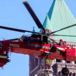 A heavy-lift Sikorsky S-64 Skycrane Helicopter in downtown Minneapolis bringing HVAC materials to the US Bank Plaza roof.