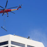 A heavy-lift Sikorsky S-64 Skycrane Helicopter in downtown Minneapolis bringing HVAC materials to the US Bank Plaza roof.