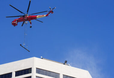 A heavy-lift Sikorsky S-64 Skycrane Helicopter in downtown Minneapolis bringing HVAC materials to the US Bank Plaza roof.