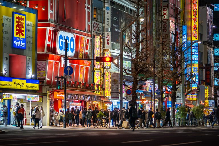 Akihabara Electric Town at Night, Tokyo 1 Pedestrians fill a Tokyo street at night beneath illuminated storefronts and neon signs.