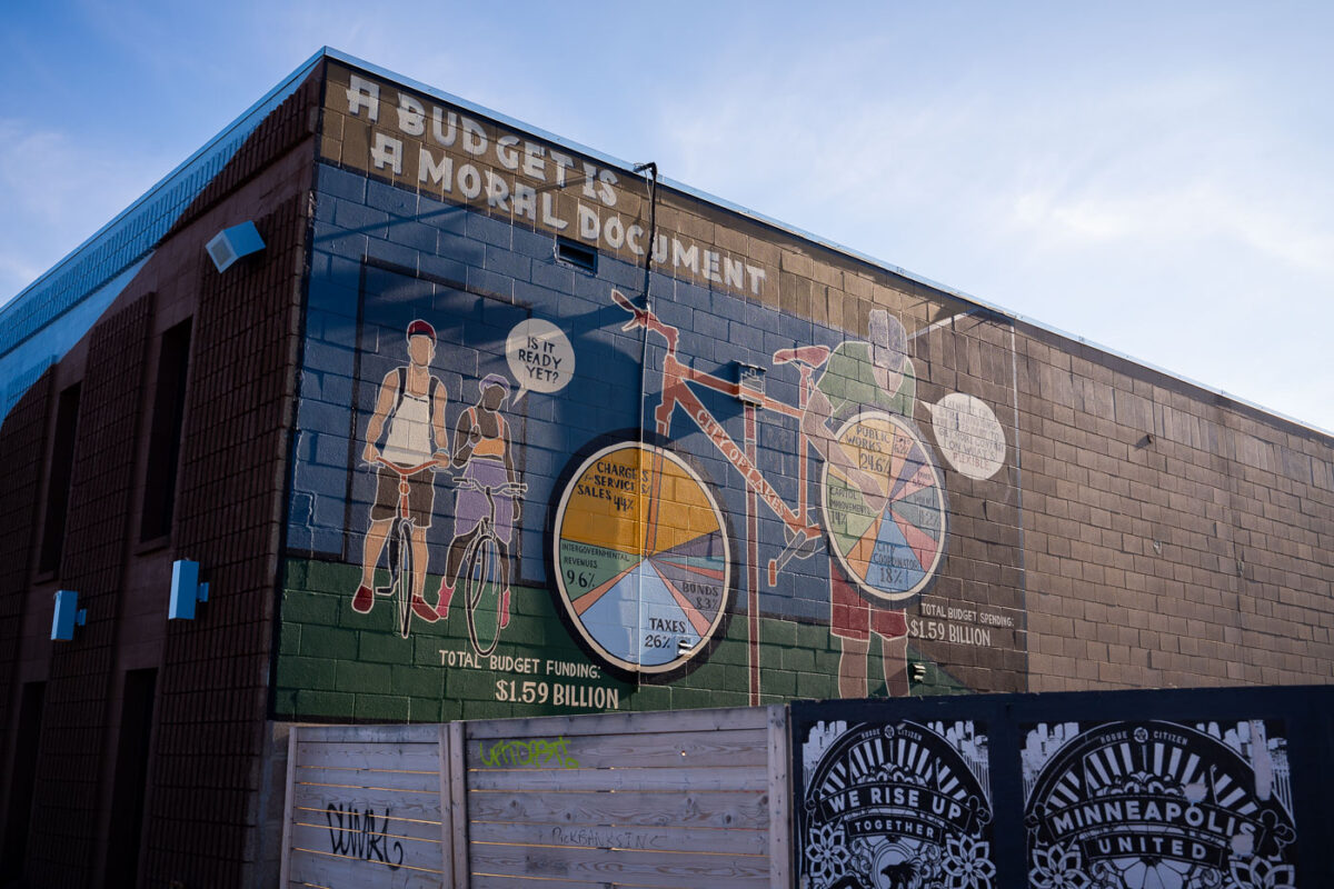 A mural on the side of a bike shop on Minnehaha Ave in Minneapolis. It reads "A Budget is a moral document".