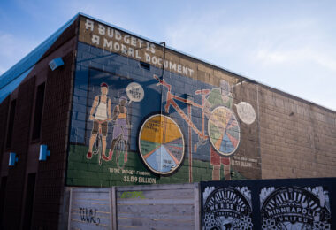 A mural on the side of a bike shop on Minnehaha Ave in Minneapolis. It reads "A Budget is a moral document".