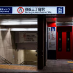 The entrance to Yotsuya-sanchome Station on Tokyo Metro’s Marunouchi Line (M11) is shown at night, featuring a clean, modern design with bright signage and red elevator doors. The station serves the Shinjuku district and connects to key destinations like Shinjuku, Ogikubo, and Tokyo Station. Braille paving and clear bilingual signs reflect Tokyo Metro’s accessibility standards and emphasis on wayfinding.