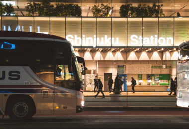 Intercity buses line up outside Shinjuku Station in Tokyo, one of the busiest rail hubs in the world and a major transfer point for long-distance coach services. The station’s west side is home to a dense cluster of express bus platforms that connect Tokyo with destinations across Honshu, Hokkaido, and Kyushu.

Captured in March 2023, the photo shows the steady flow of evening commuters moving between the station concourse and the bus loading area, illuminated by the station’s modern façade lighting. The scene reflects Shinjuku’s role not only as a metropolitan transit hub but also as a key gateway for regional travel throughout Japan.