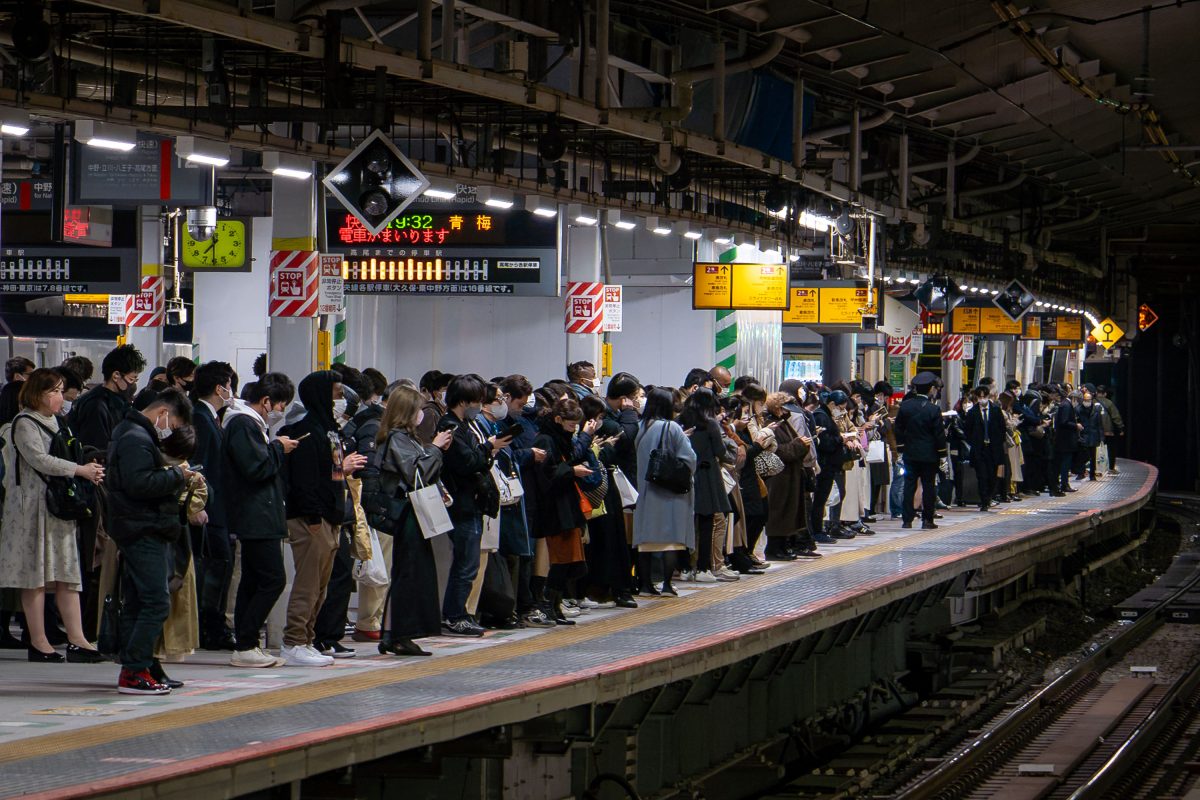 Commuters wait on a Japanese train platform during evening rush hour.