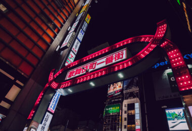 The iconic illuminated gate marking Kabukichō Ichiban-gai, photographed in Shinjuku, Tokyo. Installed in the late 1960s and redesigned several times since, the red archway has become one of the most recognizable entrances to Tokyo’s largest entertainment district.

Kabukichō developed after World War II as a planned theater district—its name comes from a never-built kabuki theater—before evolving into a dense zone of restaurants, bars, cinemas, and nightlife venues. The gate’s bright bulbs and bold lettering serve as a symbolic threshold into the neighborhood’s tightly packed streets, which remain active late into the night.