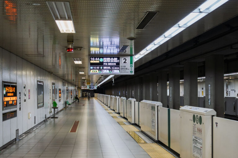 Karasuma Oike Station Platform, Kyoto 4 A quiet moment on the platform at Karasuma Oike Station, one of the key interchange points within the Kyoto Municipal Subway system. Opened in 1981 as part of the Karasuma Line, the station later became a transfer hub when the Tōzai Line opened in 1997, creating a central east–west and north–south connection beneath Kyoto’s urban core.The platform features platform-edge doors—introduced across Kyoto’s subway network to improve safety and accessibility—along with digital signage that displays through-service connections toward the northern suburbs and toward the International Conference Center. Located beneath the intersection of Karasuma-dōri and Oike-dōri, the station plays an important role in linking government offices, business districts, and cultural areas throughout central Kyoto.