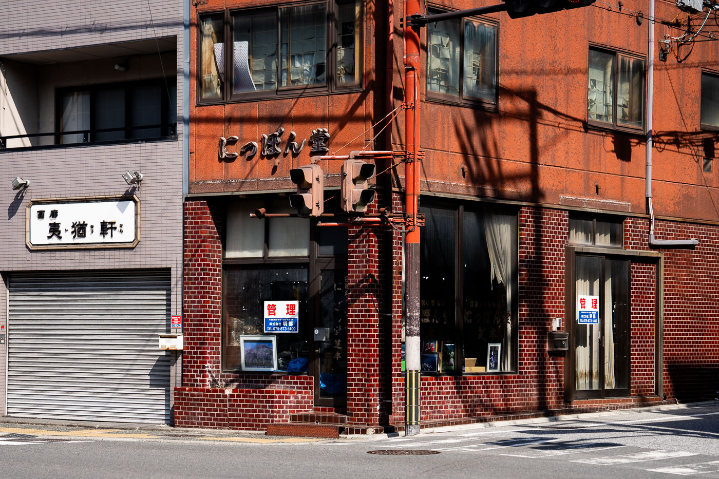 The Nippondo Building, a mid-20th century commercial structure with a weathered orange facade, stands at a street corner in Kyoto, Japan, featuring traditional signage and traffic signals.