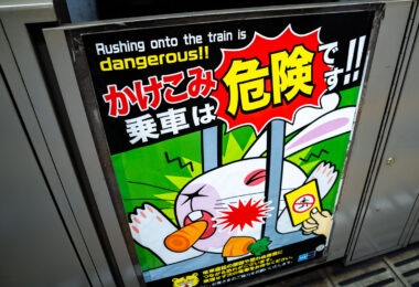 A safety poster inside a Tokyo Metro station warns passengers not to rush onto closing trains—a longstanding focus of the network’s passenger-safety campaigns. Tokyo’s subway operators, including Tokyo Metro and Toei, use a mix of mascots and bold graphic styles to discourage last-second boarding, which remains one of the most common causes of platform accidents and door malfunctions.

These posters are typically placed on or near platform screen doors, which have been installed progressively across the network since the early 2000s to reduce injuries and improve train-dwell consistency. The messaging reflects Japan’s broader public-transportation safety culture: preventing delays, protecting passengers, and maintaining precise headways in some of the most heavily used rail corridors in the world.

This particular design features a cartoon warning style common in Metro stations along lines such as the Marunouchi, Yamanote interchanges, and the Keisei connection points at Ueno and Nippori.