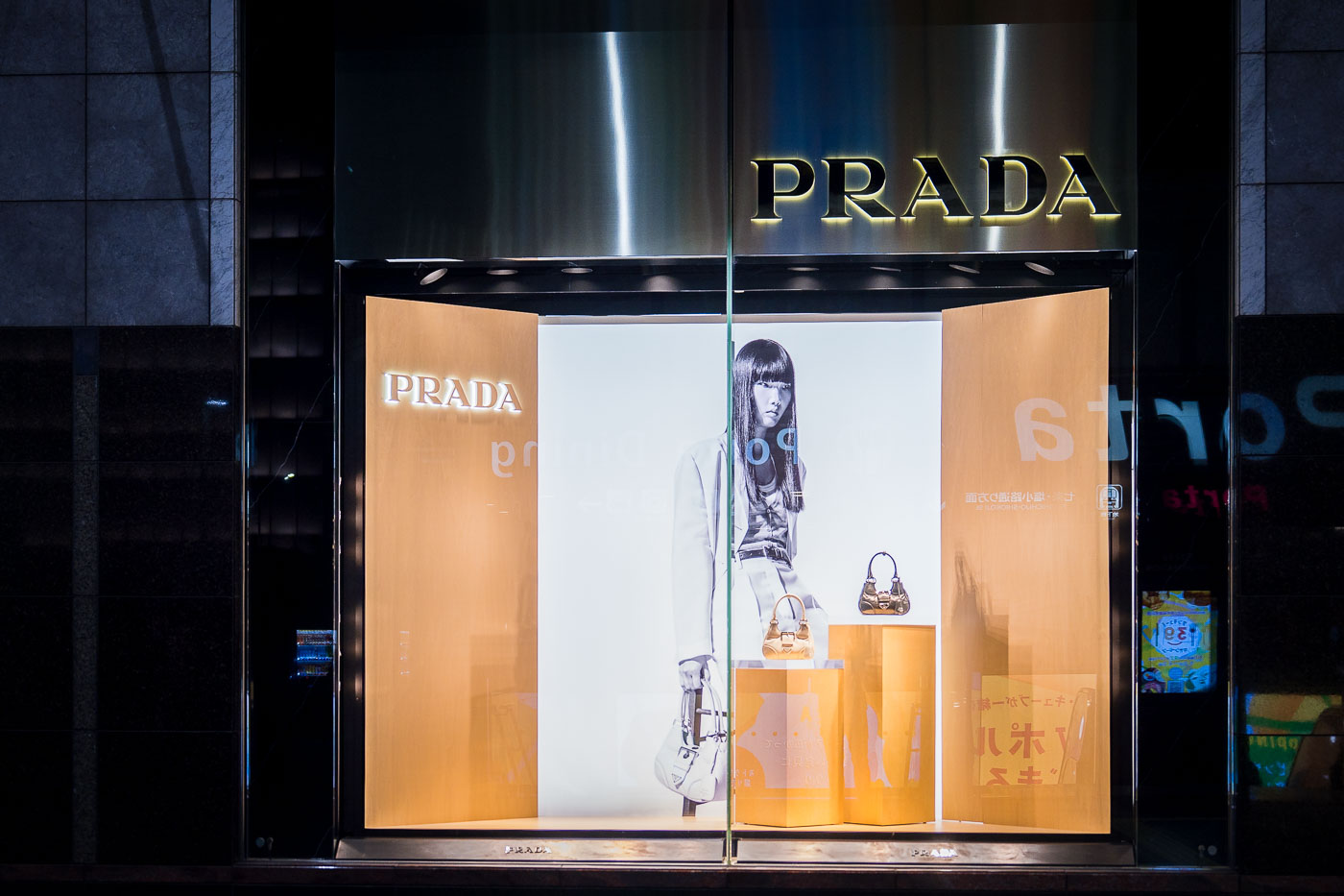 The Prada store in Kyoto, Japan, features a sophisticated storefront with a window display showcasing handbags and a model, photographed in March 2023.