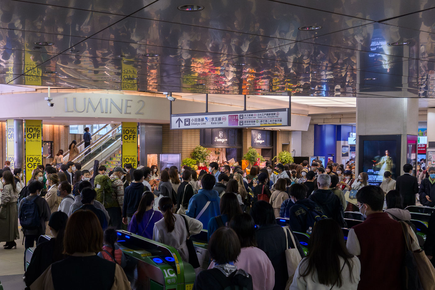 Commuters pass through the Lumine 2 entrance at Shinjuku Station, Tokyo, a major transit hub. Signage directs to Odakyu, Keio, and Toei subway lines.