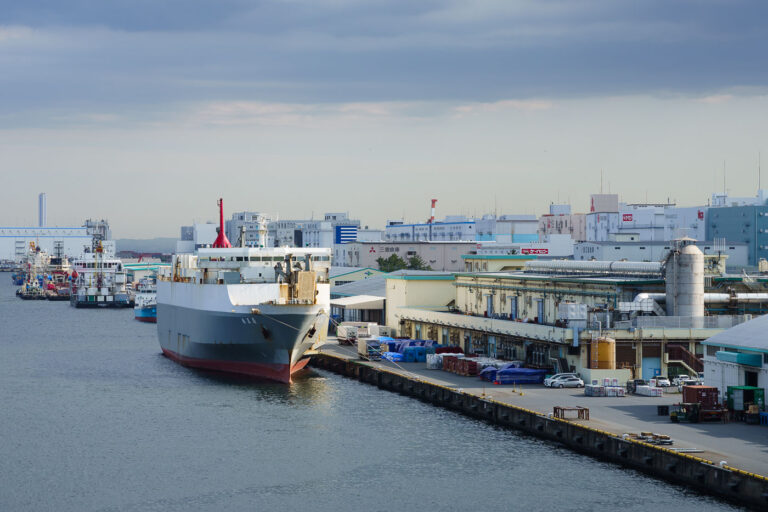 Tokyo Port: Cargo Ship Docked at Industrial Pier 1 A cargo ship is docked at an industrial pier in Tokyo Port, Japan, a major hub for international trade and logistics, with warehouses and factories visible in the background.