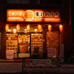 Tohoku Gyozabou, located just east of Shinjuku Gyoen National Garden, is one of many small neighborhood restaurants that serve the area’s mix of office workers, residents, and visitors. Spots like this are common throughout Shinjuku’s quieter side streets, offering regional Chinese-style dishes and set meals late into the evening, contrasting with the larger entertainment corridors to the west around Shinjuku Station and Kabukichō.

The surrounding district developed after World War II as Shinjuku expanded outward from the rail hub, creating a network of narrow commercial blocks filled with independent eateries. Many of these restaurants continue to display brightly illuminated exterior menus and lantern signage, part of the city’s longstanding street-level food culture that encourages casual walk-in dining.