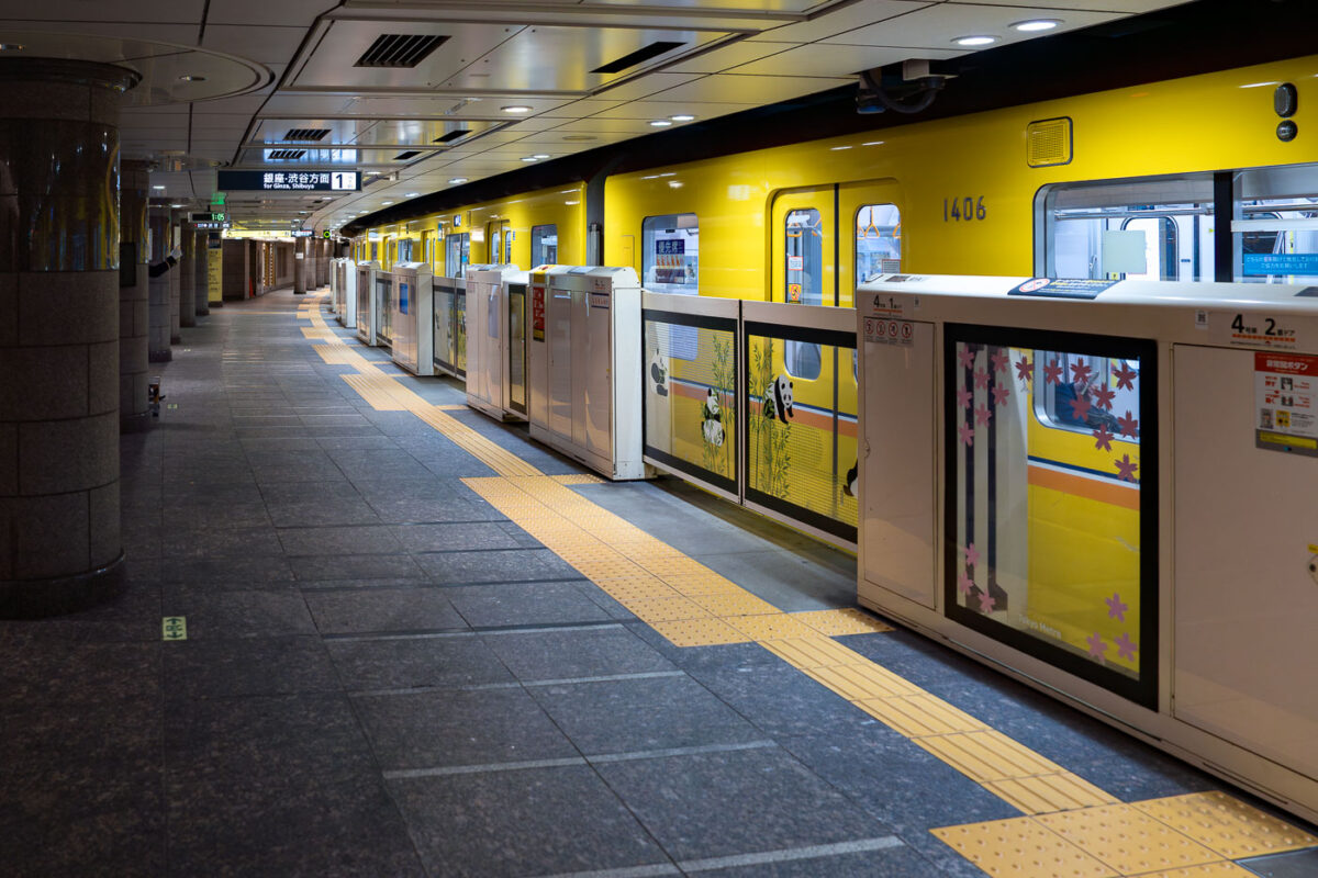 A yellow Tokyo Metro Ginza Line train with panda decals waits at a station platform in Japan. The Ginza Line is Tokyo's oldest subway line.