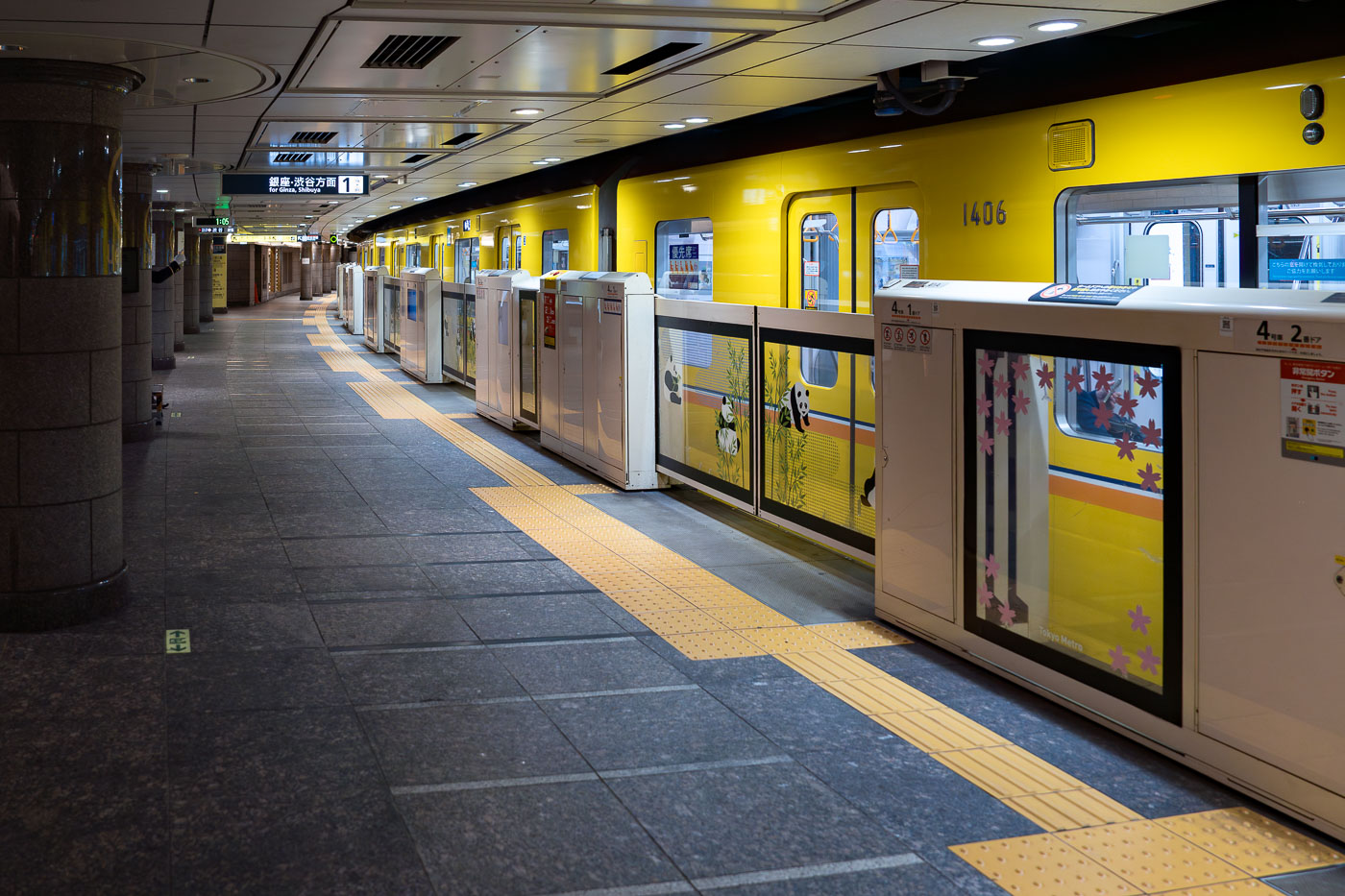 A yellow Tokyo Metro Ginza Line train with panda decals waits at a station platform in Japan. The Ginza Line is Tokyo's oldest subway line.