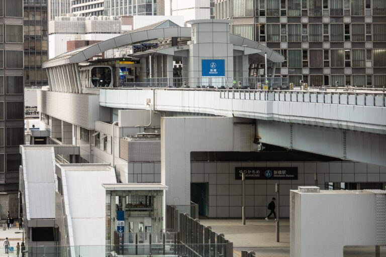 Shimbashi Station and the Elevated Yurikamome Line in Tokyo 2 Shimbashi Station serves as a key interchange between Tokyo’s dense urban rail systems, connecting JR East lines with the Yurikamome automated transit route to Odaiba. The elevated Yurikamome track, seen here curving above the city streets, is a fully driverless, rubber-tired train line that opened in 1995 to link Tokyo’s central business districts with its reclaimed waterfront developments.This structure’s sleek metallic architecture and tiered design reflect Japan’s approach to maximizing space efficiency in high-density transport corridors. The network below includes the JR Yamanote Line, Tokyo Metro Ginza Line, and the Toei Asakusa Line, making Shimbashi one of the most vertically integrated transit hubs in Japan.