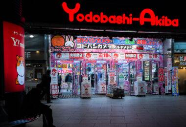 Yodobashi-Akiba, photographed in March 2023, is one of Tokyo’s largest electronics retail complexes and a major landmark in the Akihabara district. Opened in 2005 as part of a wider redevelopment effort around JR Akihabara Station, the multi-story store consolidated several specialty floors—computers, cameras, gaming, home appliances, musical instruments—into a single destination that helped redefine the area’s retail identity in the 2000s.

Its brightly illuminated entrance, typically covered in seasonal and promotional signage, reflects the competitive electronics market that shaped modern Akihabara. The building also connects directly to the Tsukuba Express line and sits beside the redevelopment zone that transformed the district from its postwar reputation as “Electric Town” into a mix of technology retail, office towers, and entertainment venues.
