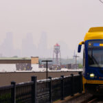 Downtown Minneapolis barely visible as a Metro Transit Light Rail train cross the bridge.