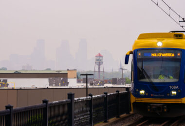Downtown Minneapolis barely visible as a Metro Transit Light Rail train cross the bridge.