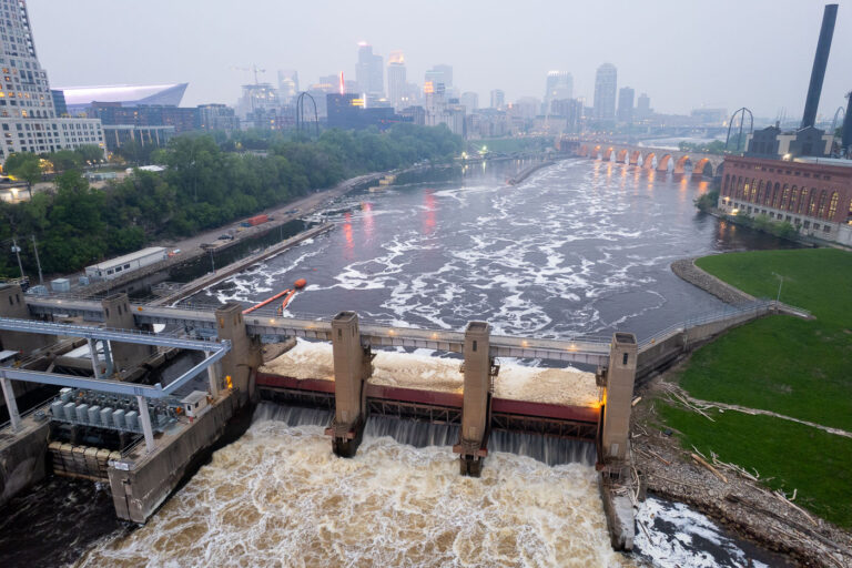 Minneapolis Lock and Dam Under Canadian Wildfire Smoke 4 The Minneapolis Lock and Dam on the Mississippi River is obscured by haze from Canadian wildfire smoke, impacting air quality in the downtown area. Constructed in the early 20th century, the lock and dam system was designed to improve navigation on the river, facilitating the transport of goods and materials. Today, it continues to play a role in managing water levels and supporting barge traffic, though its visual presence is altered by atmospheric conditions. The Stone Arch Bridge, a historic landmark, is visible in the background, further contextualizing the industrial and infrastructural history of Minneapolis.