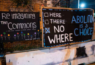 A "Abolition is a choice" banner hanging on the Third Precinct. A sign referencing the cities plans to re-build a replacement third precinct.