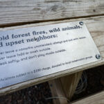 A notice on a picnic table at a Getaway campground in Kettle River. "Avoid forest fires, wild animals, and upset neighbors: 1. Never leave a campfire unattended; always put out the water. 2. Never leave food or trash outside. 3. Speak softly, and don't play music outside.