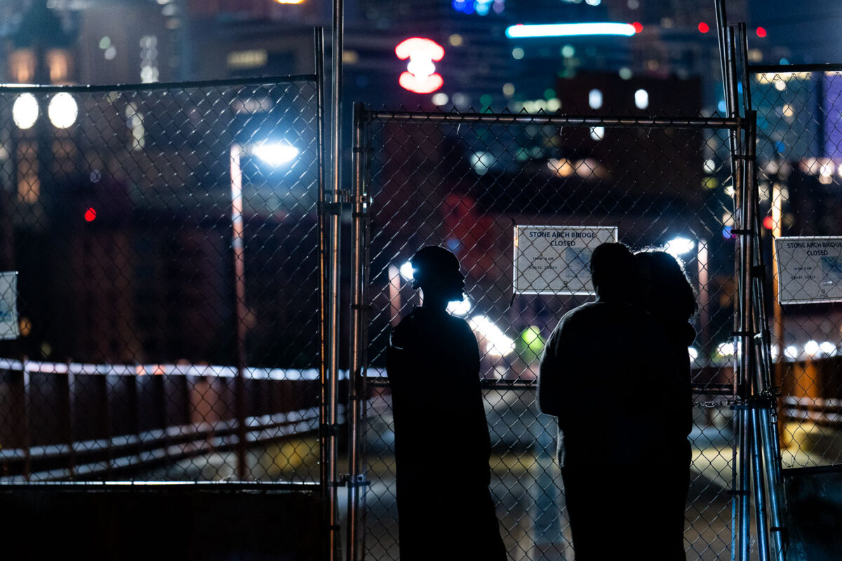 A group looks at the newly installed fence at the end of the Stone Arch Bridge.