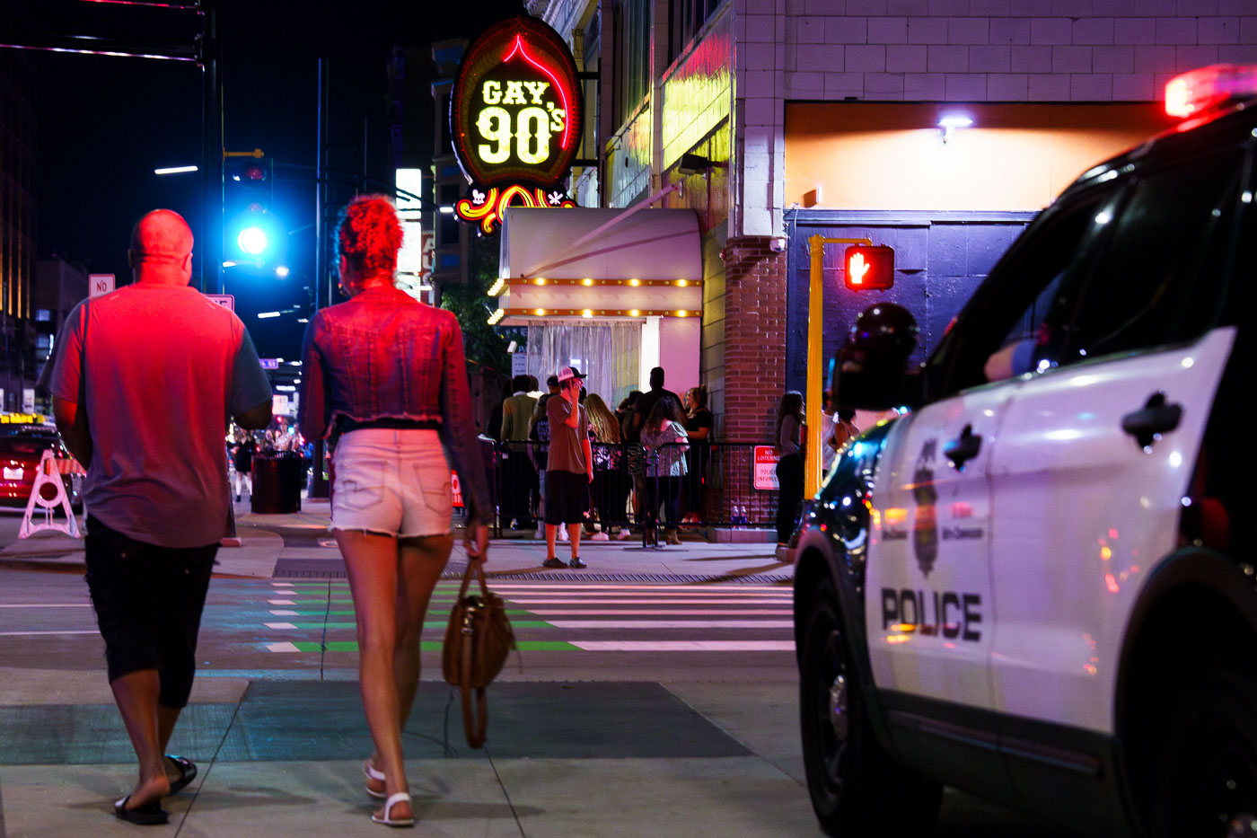 Couple walk in front of nightclub signs