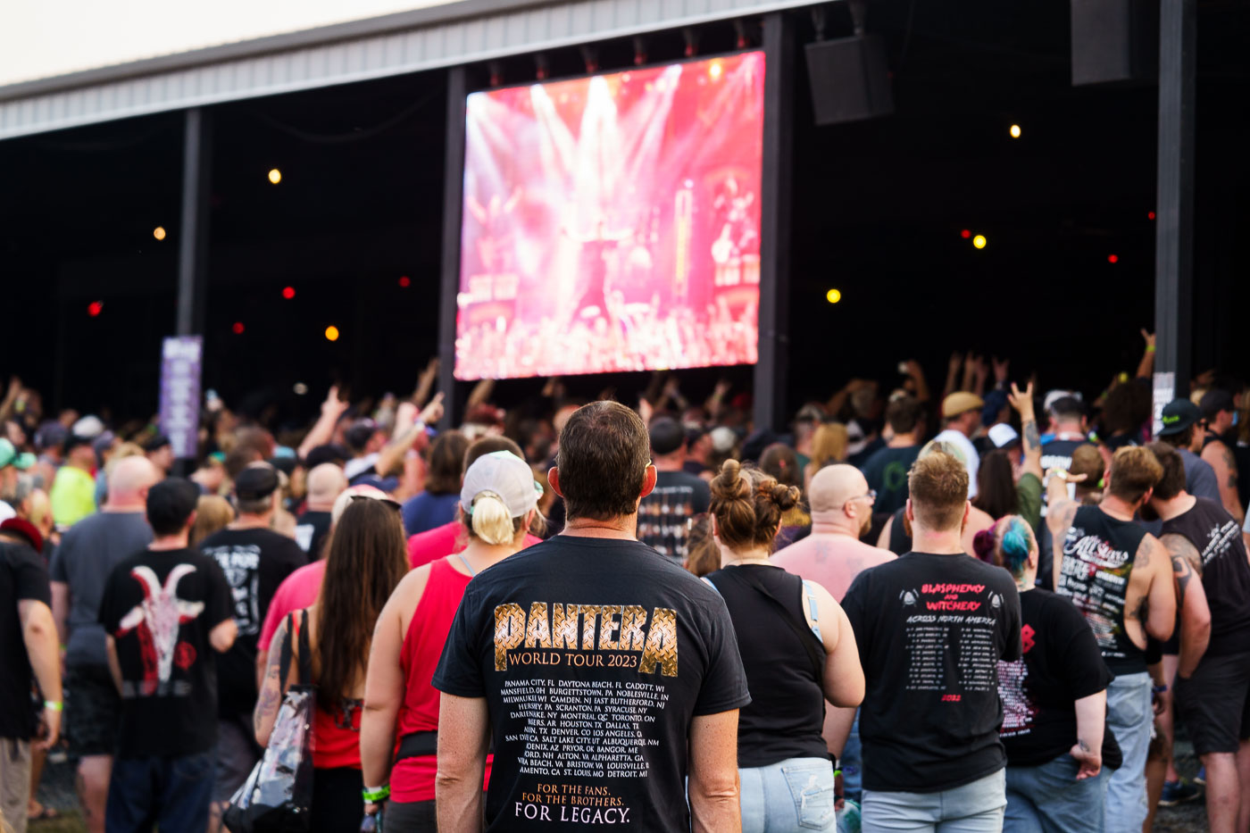 Attendees gather for the Pantera World Tour 2023 at Rock Fest in Cadott, Wisconsin. The festival, held annually, is a significant event for heavy metal music enthusiasts in the Midwest. This particular concert marked a notable stop on the band's reunion tour, celebrating their enduring legacy in the genre. The shirt worn by the individual in the foreground lists numerous tour dates and locations, underscoring the global reach of the band's 2023 performances.