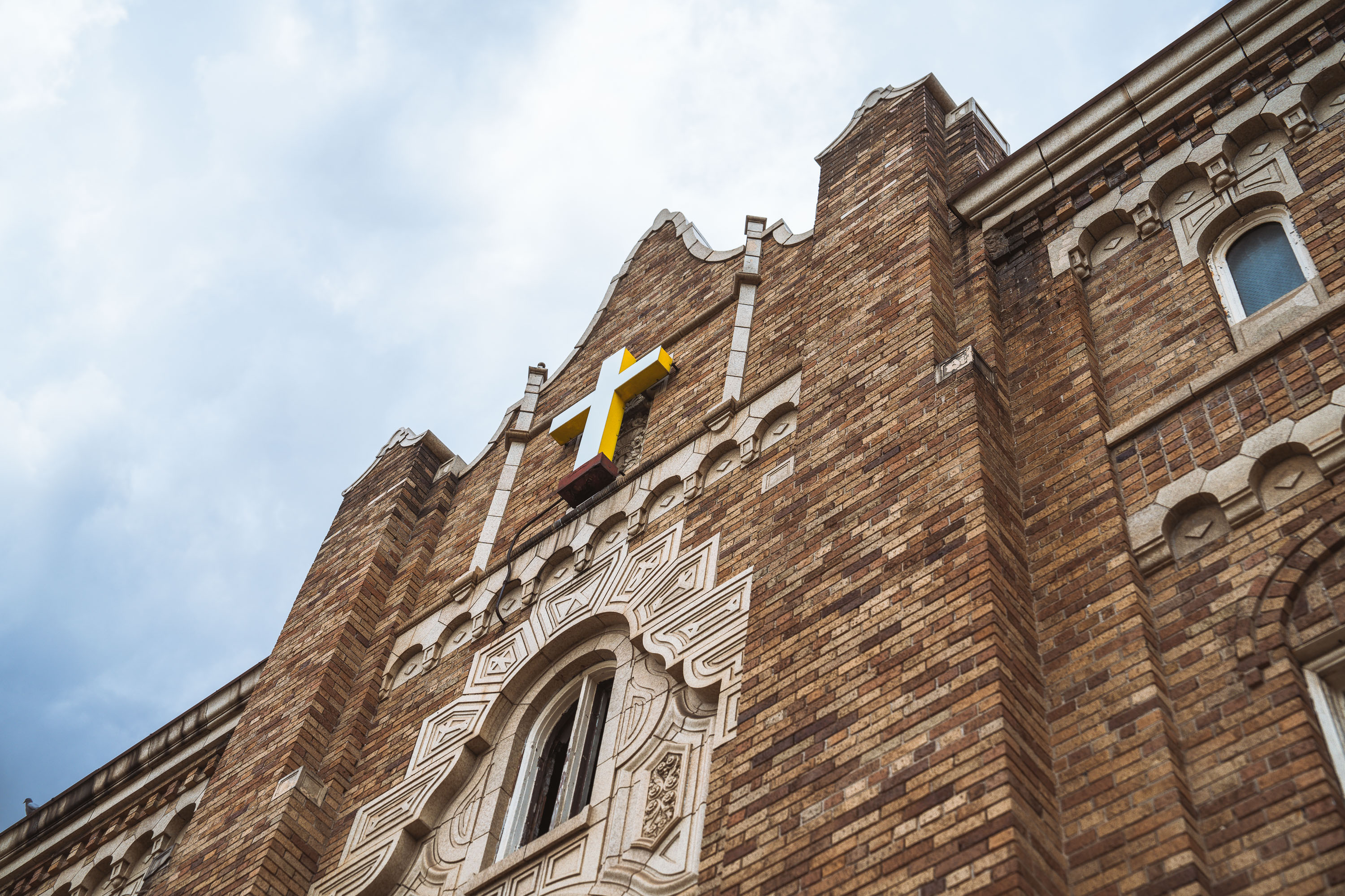 A yellow cross mounted on the brick facade of the abandoned Zenith Theater in Milwaukee.
