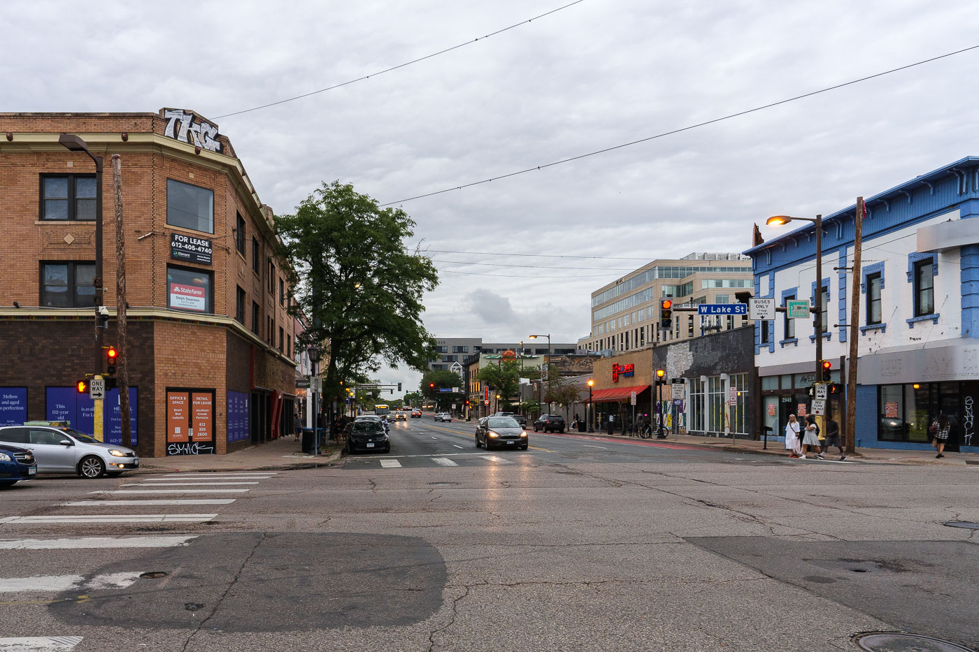 The intersection of Hennepin Avenue and W Lake Street in Uptown Minneapolis, a commercial hub with brick buildings and storefronts, on an overcast day.