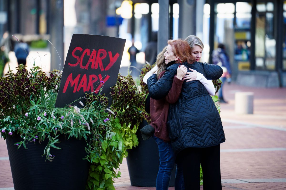 A Hug Beside the “Scary Mary” Sign at Mary Moriarty Rally