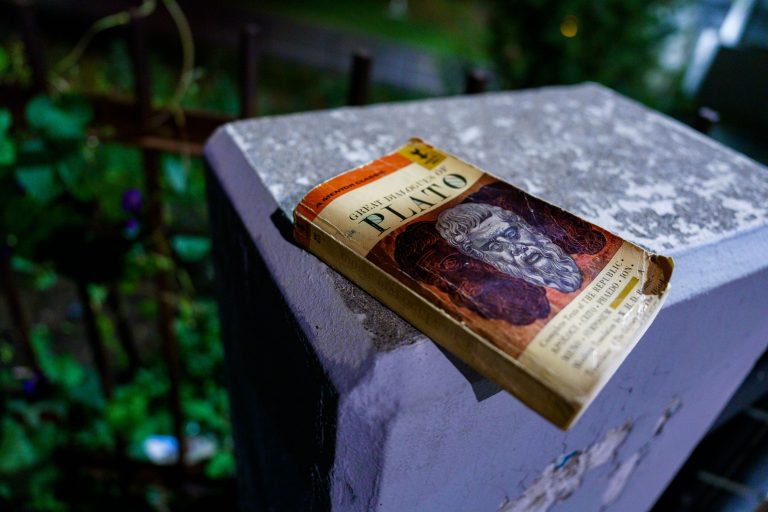 Great Dialogues of Plato Paperback, Uptown Minneapolis 2 A weathered copy of Plato's complete works rests on a concrete surface surrounded by green foliage.