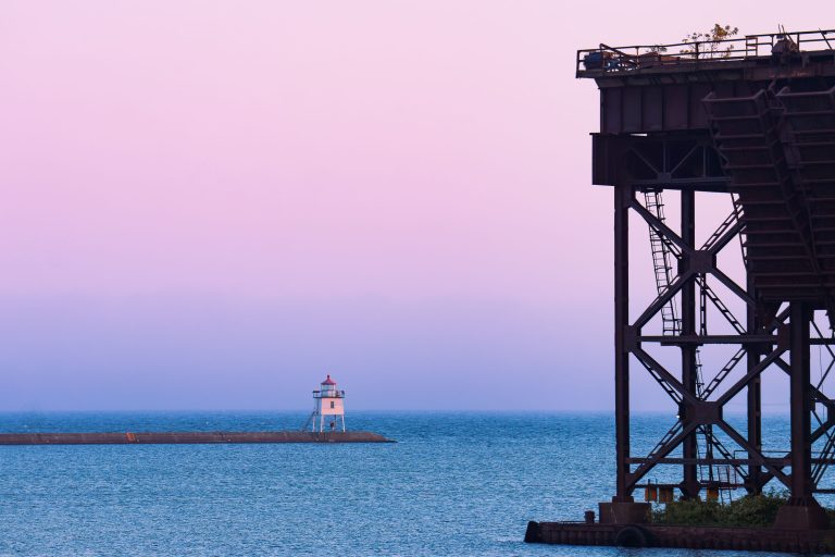 Two Harbors East Breakwater Light, Minnesota 1 Steel ore dock structure silhouetted against twilight sky with lighthouse on Lake Superior horizon, Two Harbors, Minnesota.
