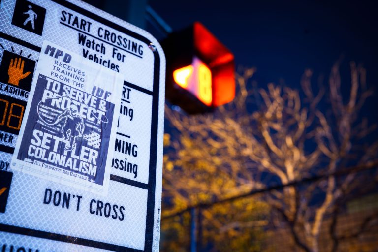 "MPD Trains with IDF" Sticker, Minneapolis Crosswalk Sign 4 Political sticker on street sign critiquing Minneapolis Police Department training practices and settler colonialism.