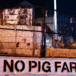 A banner reading "NO PIG FARM" on a barricade around the former Minneapolis police third precinct. The building was burned in the 2020 Uprising following the murder of George Floyd. It's sat vacant ever since. November 2023.
