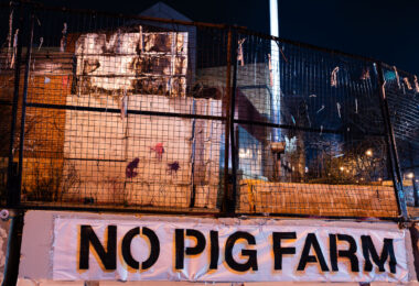 A banner reading "NO PIG FARM" on a barricade around the former Minneapolis police third precinct. The building was burned in the 2020 Uprising following the murder of George Floyd. It's sat vacant ever since. November 2023.