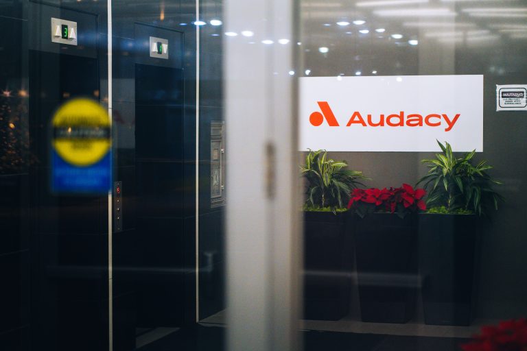 Audacy Office Lobby, Downtown Minneapolis 3 Audacy office entrance in downtown Minneapolis displays the company's illuminated logo above potted plants.