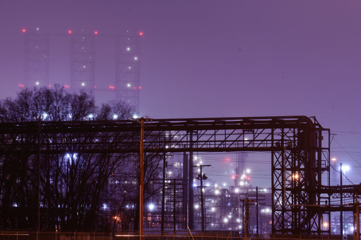 The BP Whiting Refinery in Indiana is illuminated at night, its complex network of pipes and towers visible through fog. It is the largest refinery in the Midwest and BP's largest globally.