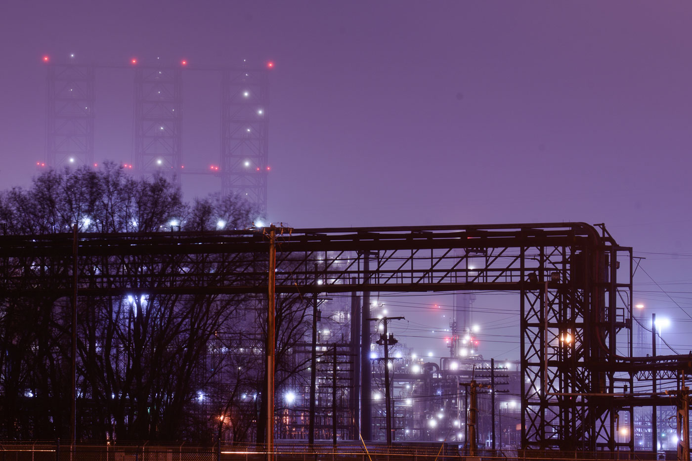 The BP Whiting Refinery in Indiana is illuminated at night, its complex network of pipes and towers visible through fog. It is the largest refinery in the Midwest and BP's largest globally.