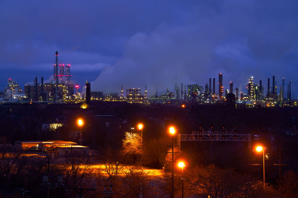 The BP Whiting Refinery complex in Hammond, Indiana, is illuminated at dusk, with steam rising from its towers. It is BP's largest refinery globally and the largest in the Midwest.