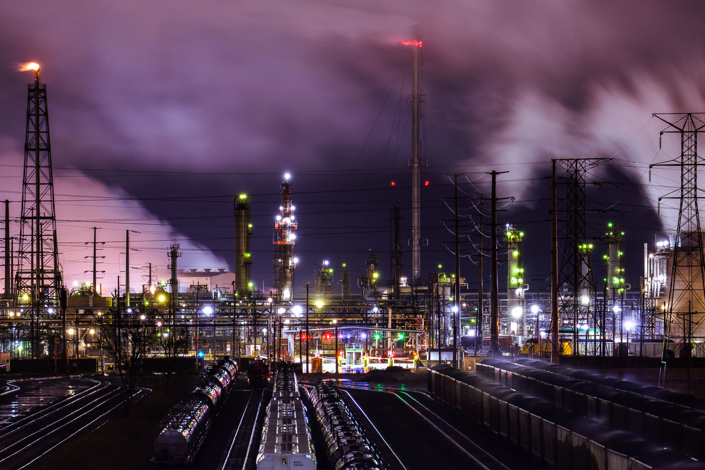 The BP Whiting Refinery in Indiana, the Midwest's largest oil refinery, is illuminated at night with a flare stack burning and steam rising.