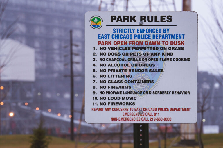 East Chicago Park Rules Sign in Marktown 2 Park rules sign in Marktown, East Chicago, Indiana, lists regulations enforced by the East Chicago Police Department, including prohibitions on vehicles on grass, pets, alcohol, and firearms.