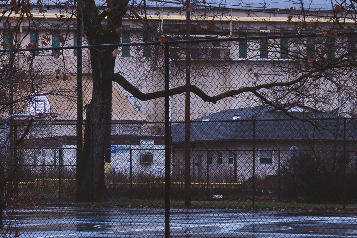 Marktown, East Chicago, Indiana: A basketball court and industrial buildings are seen through a chain-link fence.