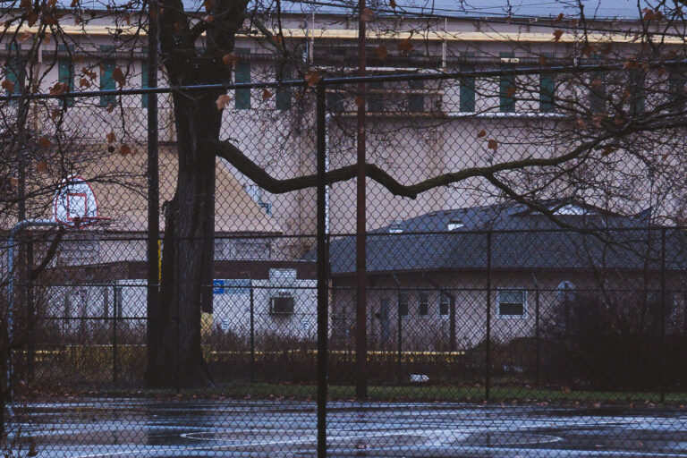 Marktown, East Chicago: Basketball Court and Industrial Buildings 3 Marktown, East Chicago, Indiana: A basketball court and industrial buildings are seen through a chain-link fence.