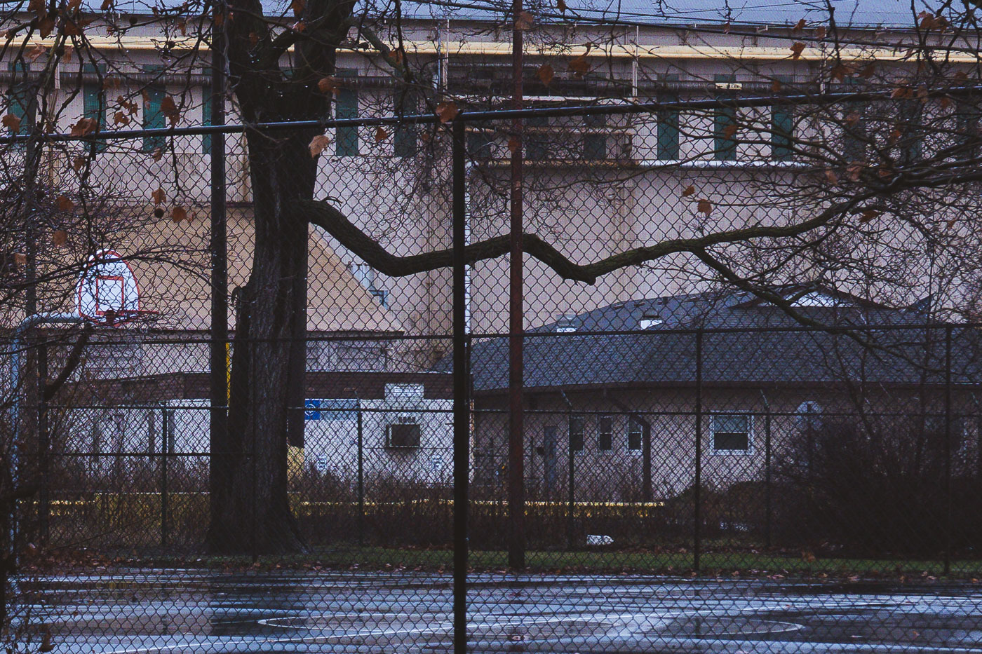 Marktown, East Chicago, Indiana: A basketball court and industrial buildings are seen through a chain-link fence.