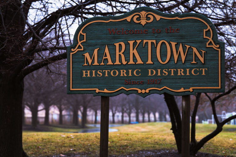 Welcome to Marktown, Indiana sign 1 Welcome to Marktown, Indiana. Marktown is on the National Register of Historic Places.
The town was created by Clayton Mark, owner of the Clayton Mark and Company that made steel pipes, to house employees. The town is bordered by a US Steel plant and the largest BP refinery in the world. The town is known as the only town in North America where residents drive on the sidewalks and walk in the street.